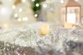 Unfocused shot of Christmas decorations. Shiny sparkling fabric, blurry lantern and candle, garland lights bokeh.