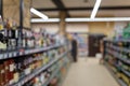 Supermarket interior. Blurry hypermarket, mall or shopping center background. Rows and shelves of grocery department with alcohol
