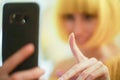 Unfocused soft blurred image in profile of a blonde girl using a smartphone