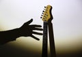 Unfulfilled dreams concept. Electric guitar on the shadow with man`s hand. Musician under the spotlight. Creative style photo wit Royalty Free Stock Photo