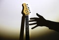 Unfulfilled dreams concept. Electric guitar on the shadow with man`s hand. Musician under the spotlight. Creative style photo wit Royalty Free Stock Photo