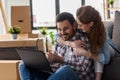 Ung couple moving in new home. Sitting and relaxing after unpacking. Looking something on laptop Royalty Free Stock Photo