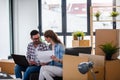 Ung couple moving in new home. Sitting and relaxing after unpacking. Looking something on laptop Royalty Free Stock Photo