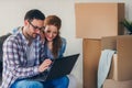 Ung couple moving in new home. Sitting and relaxing after unpacking. Looking something on laptop Royalty Free Stock Photo