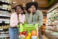 Unhappy African American Couple Standing With Shopping Cart In Supermarket Royalty Free Stock Photo