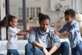 Unhappy African American father ignoring noisy children, feeling exhausted