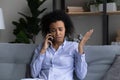 Unhappy African American woman talking on phone at home Royalty Free Stock Photo