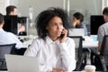 Unhappy African American woman talking on phone at workplace Royalty Free Stock Photo