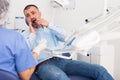 Unhappy american man in medical chair complains of toothache