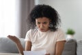 Unhappy angry African American woman reading paper letter, bad news