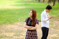 Unhappy angry woman waiting to her boyfriend playing game online on smart phone, Couple in park for leisure time together concept Royalty Free Stock Photo