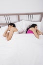 Unhappy Asian couple sleeping back to back in bed