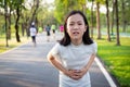 Unhappy asian little cute girl holding her hands on belly,suffers from stomach pain,colic after running,exercise in outdoor park,