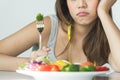 Unhappy asian women is on dieting time looking at broccoli on the fork. girl do not want to eat vegetables and dislike taste of Royalty Free Stock Photo