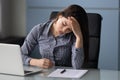 Unhappy attractive businesswoman suffering from headache at work at laptop. Royalty Free Stock Photo