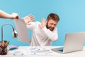 Unhappy bearded man analyst hiding from extra work sitting at workplace with laptop, holding out hands rejecting to sign out Royalty Free Stock Photo