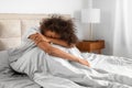 Unhappy black lady covering face struggling to wake up indoor