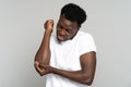 Unhappy Black man in t-shirt suffers her elbow joint pain or arm bone osteoporosis, pinched nerve Royalty Free Stock Photo