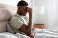 Unhappy black man in bed pressing fist to forehead indoor Royalty Free Stock Photo