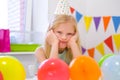 Unhappy blonde caucasian girl with boring face near birthday rainbow cake. Festive colorful background. Bad birthday Royalty Free Stock Photo