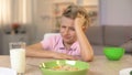 Unhappy boy looking oatmeal with disgust, unappetizing food, healthy breakfast