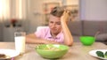 Unhappy boy looking oatmeal with disgust, unappetizing food, healthy breakfast Royalty Free Stock Photo