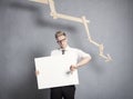 Unhappy businessman showing panel in front of descending graph.