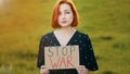 Unhappy caucasian young redhead woman activist hold demonstrating banner with inscription stop war sad pretty girl stand Royalty Free Stock Photo