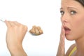 Unhappy Cautious Young Woman Holding a Spoonful of Brown Sugar Cubes