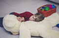 Unhappy Child boy lies on the floor at home or in kindergarten among toys and is sad or falls asleep. Social concept of childhood