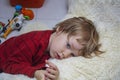 Unhappy Child boy lies on the floor at home or in kindergarten among toys and is sad or falls asleep. Social concept of childhood