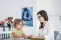 Unhappy child refusing to do exercises from a book with a school