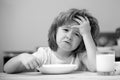 Unhappy child sit at table at home kitchen have no appetite. Caucasian toddler child boy eating healthy soup in the Royalty Free Stock Photo