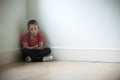 Unhappy Child Sitting In Corner Of Room