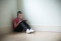 Unhappy Child Sitting In Room With Digital Tablet