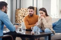 Unhappy couple sitting on sofa at therapy session in therapists office