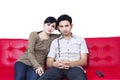 Unhappy couple watching TV and sitting on red sofa Royalty Free Stock Photo