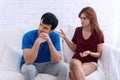 Unhappy couples at home. man and beautiful young woman are sitting on white sofa together. Husband has attitude annoyed