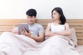 Unhappy couples at home. Handsome using tablet ignoring his girlfriend feeling unsatisfied in the bedroom. Couple having Royalty Free Stock Photo