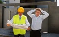 Unhappy customer in stress and constructor foreman worker with helmet and vest arguing outdoors on new house building blueprints