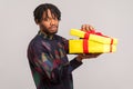 Unhappy disappointed african guy with dreadlocks holding unpacked gift box with frustrated dissatisfied face, upset with present