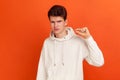 Unhappy disappointed teenager in casual hoodie showing a little gesture with fingers, asking parents for little more freedom and