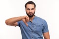 Unhappy dissatisfied man with beard showing thumbs down dislike gesture, symbol of disagree, giving feedback