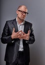 Unhappy doubt busuness man in black suit and glasses showing the palm refusing sign on grey background. Closeup