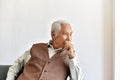 Unhappy elderly asian man with carefully thought gesture, Lonely old man looking out the window worry about life problem. Royalty Free Stock Photo