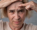 Unhappy elderly woman pointing at wrinkles on her forehead.