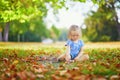 Unhappy and emotional toddler girl sitting on the ground in park