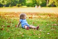 Unhappy and emotional toddler girl sitting on the ground in park