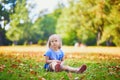 Unhappy and emotional toddler girl sitting on the ground in park