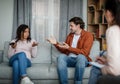 Unhappy european husband swears at black wife with smartphone on consultation with psychologist in clinic Royalty Free Stock Photo